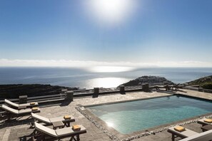 A pool area with lounge chairs and a view of the sea. - Gerofinikas Complex (Sifnos)