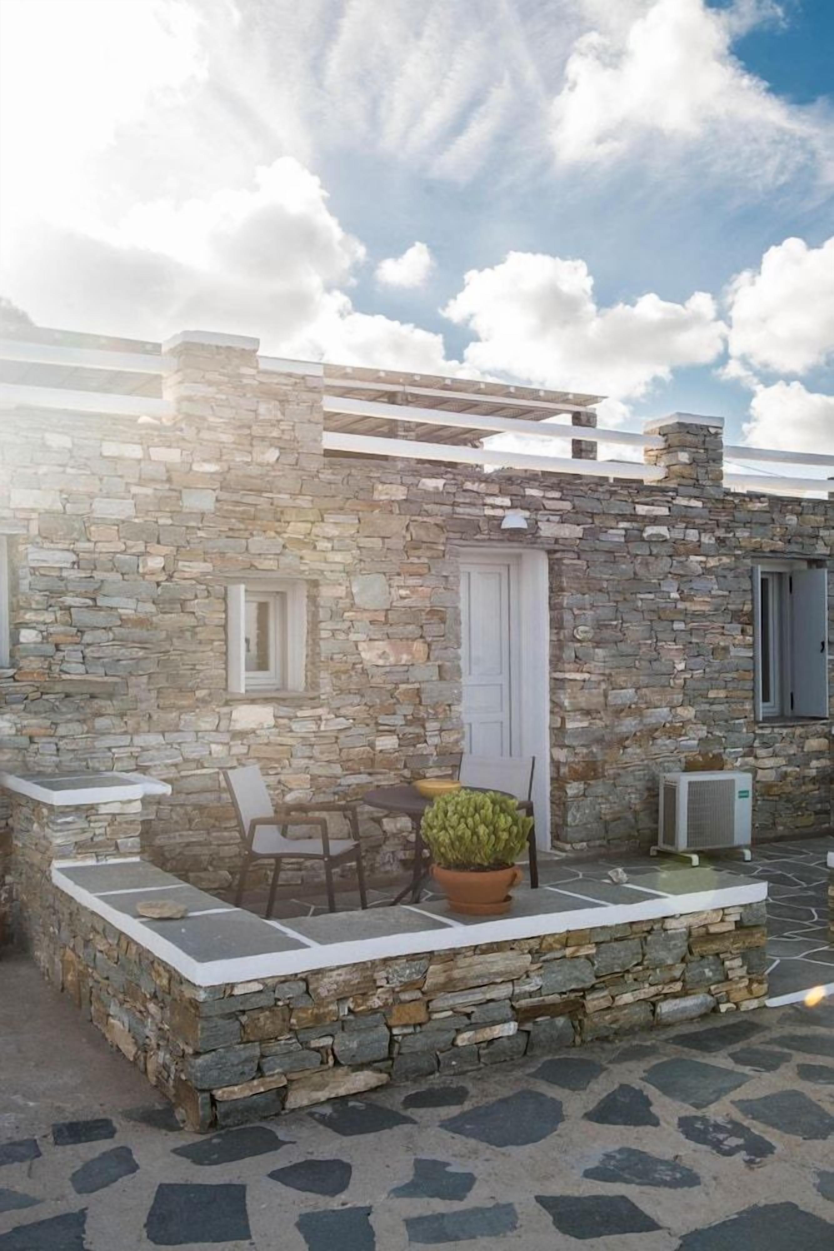 A stone building with a small patio area, a door, and a window.