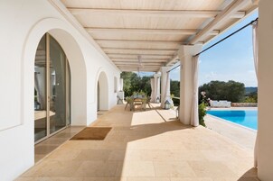 Un espacio al aire libre cubierto con piscina, una mesa con sillas y vistas del paisaje circundante.