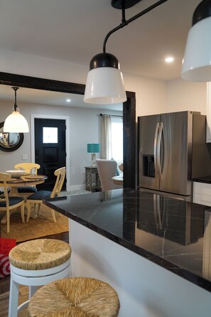 A modern kitchen with a black countertop, stainless steel appliances, and a dining area with a round table and chairs. - Serene 4-bedroom house with central AC and heating in charming Norwalk (Norwalk)