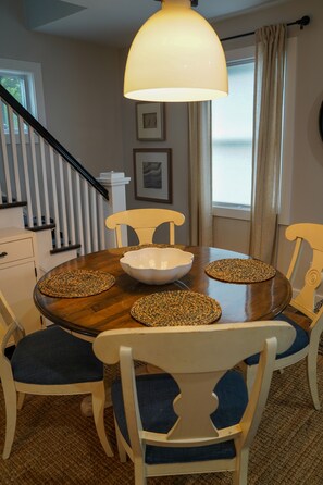A dining area with a round table, white chairs, a central white bowl, and woven placemats. - Serene 4-bedroom house with central AC and heating in charming Norwalk (Norwalk)