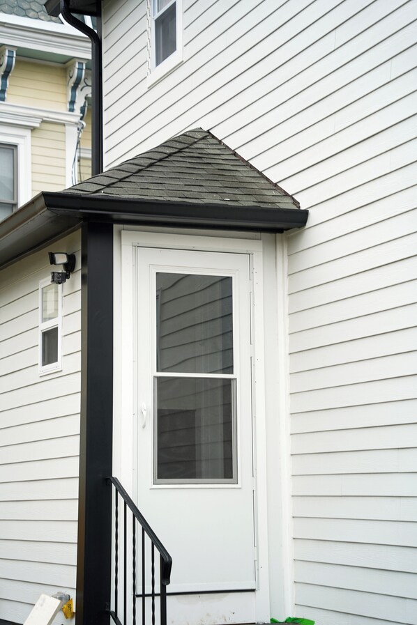 A white door with a black frame, a small window above it, and a black railing in front.