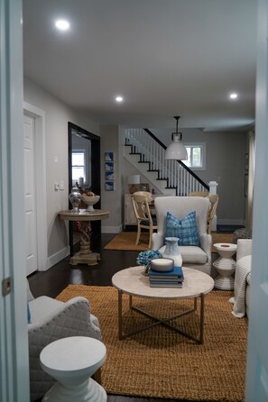 A modern living room with a staircase, a coffee table with books, and a decorative vase.