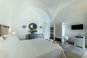 A bedroom with a bed, a dresser, a mirror, a television, and a wardrobe. - Masseria Don Luigi (Fasano)