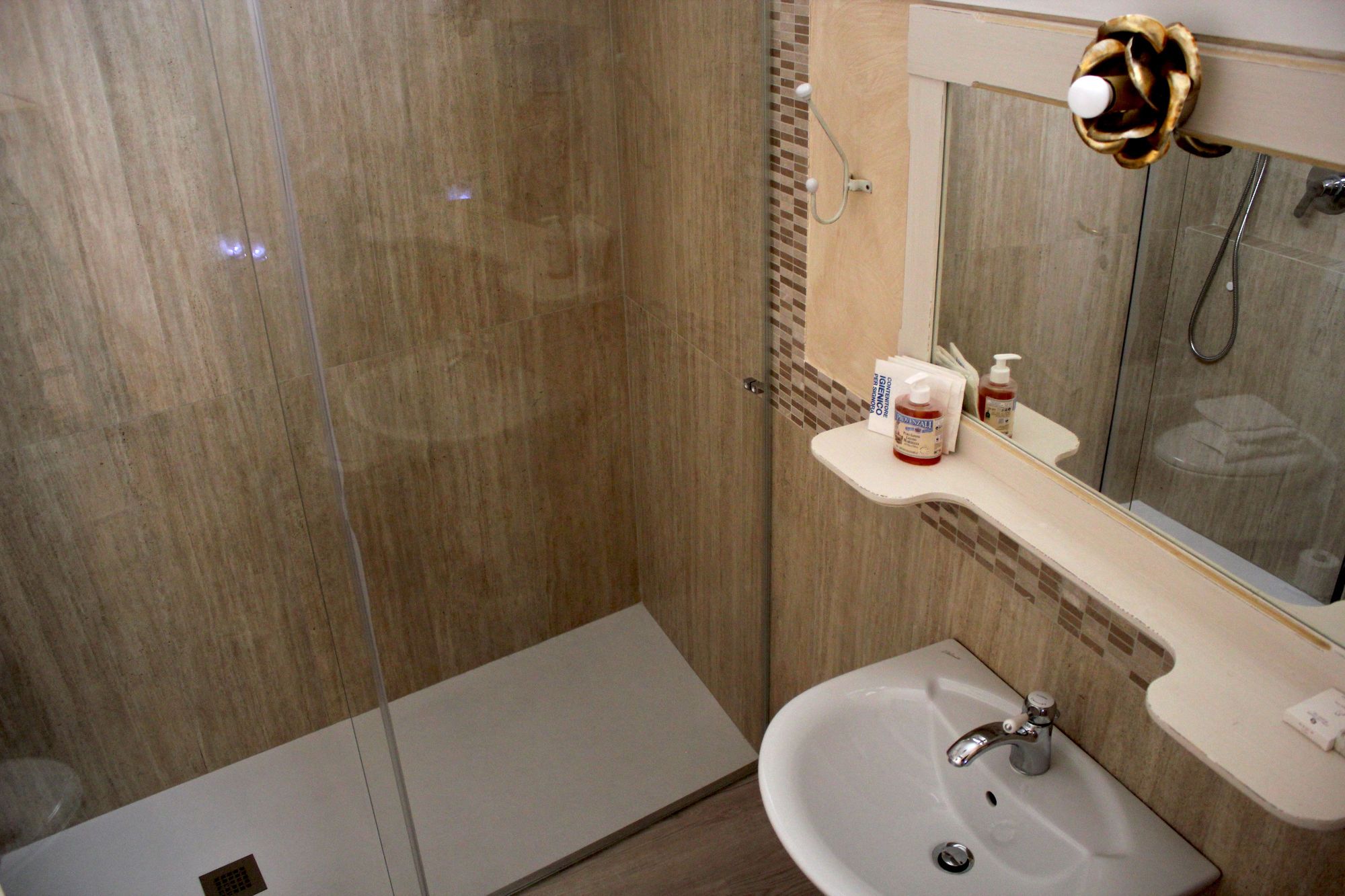Un bagno con doccia, lavandino e specchio.