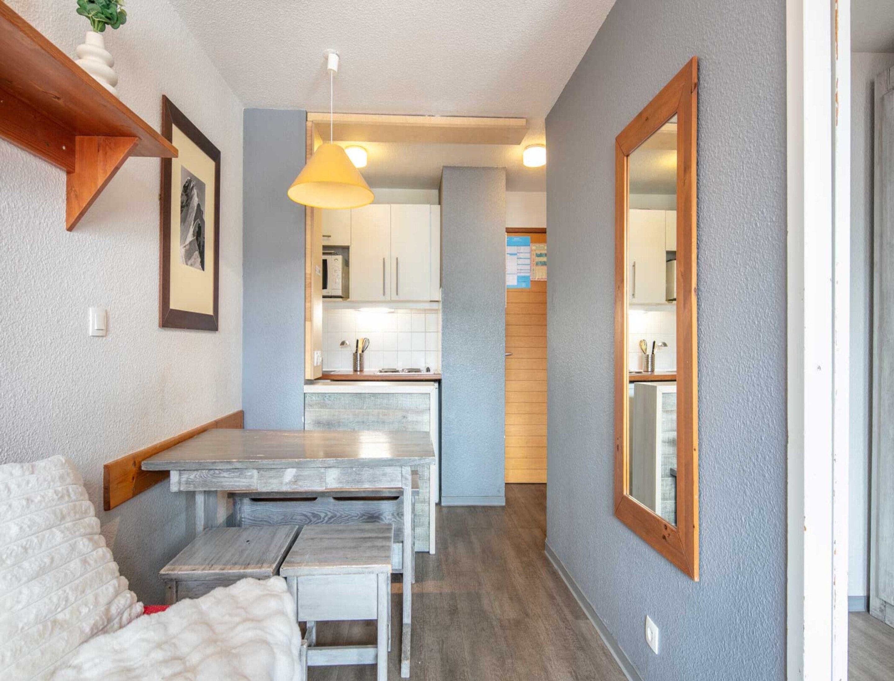 Una cocina compacta con armarios blancos, encimera de madera y una lámpara colgante amarilla.