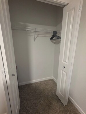 A closed closet with a white door, a metal shelf, and a carpeted floor. - Charming 2-bedroom House Rental in Calgary - Welcome to Homely Harbour! (Calgary)
