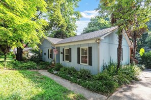 A single-story house with a front porch, a flag, and a well-maintained lawn. - Moroccan Retreat - Fire Pit & Private Yard (Raleigh)
