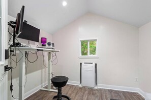 A room with a desk, computer, and a window with a view of trees. - Moroccan Retreat - Fire Pit & Private Yard (Raleigh)