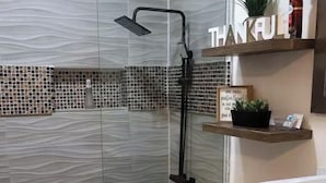 Un baño moderno con cabina de ducha de vidrio, un inodoro blanco y un mueble negro.