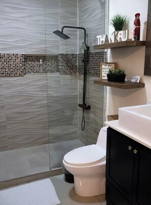 A modern bathroom with a glass shower enclosure, a white toilet, and a black cabinet. - Wonderful Ridgecrest Home (Ridgecrest)