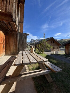 A wooden building with a picnic table outside, a mountain in the background, and a clear sky. - Demi chalet avec vue sur les pistes (Dévoluy)