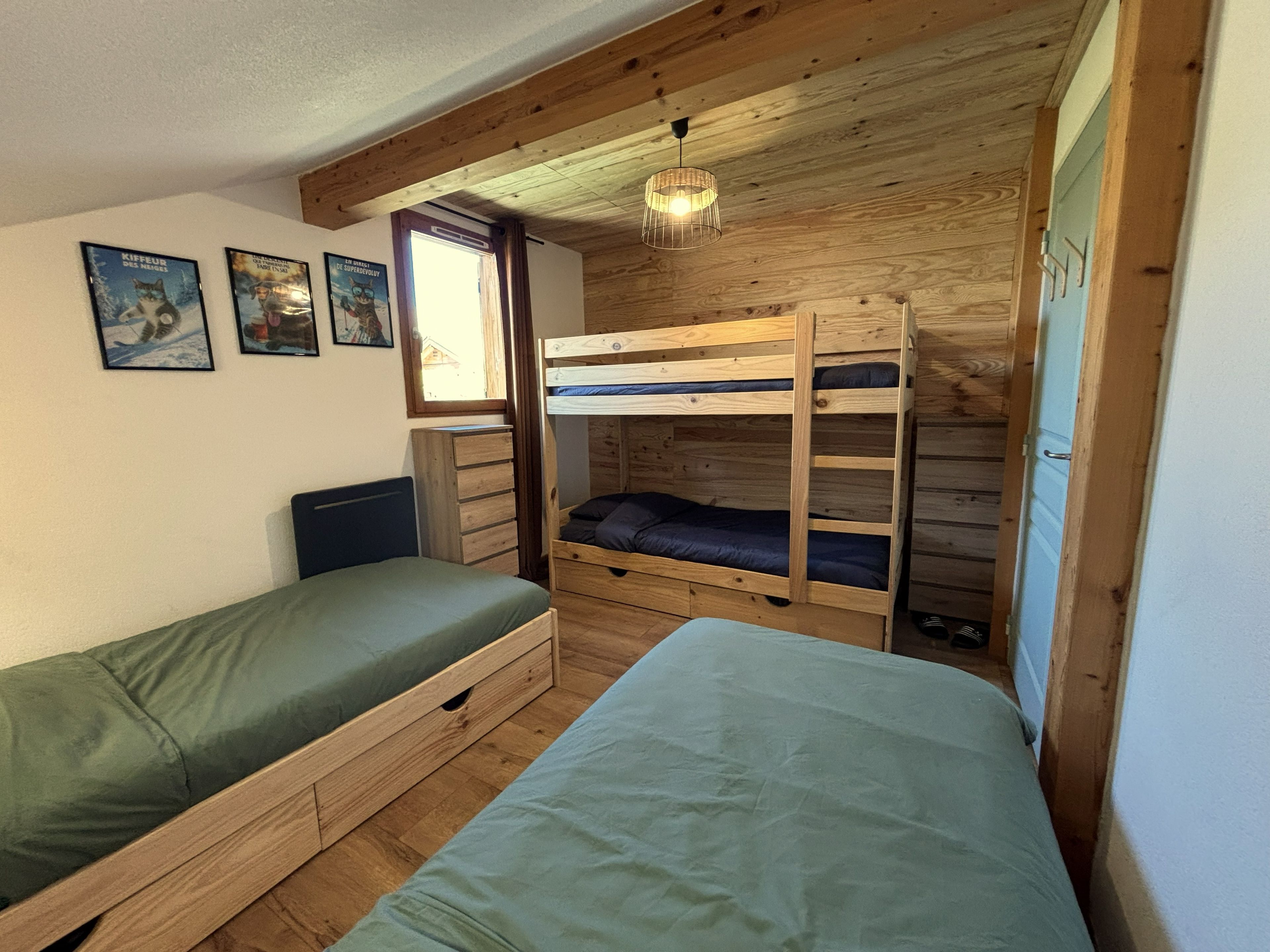Une chambre avec des lits superposés, une commode et une fenêtre.
