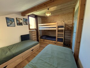 Quarto com beliches, cômoda e janela.