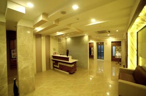 A spacious lobby with a reception desk, polished marble floors, and a modern ceiling design. - Oyo Rooms NTR Health University (Penumuluru)