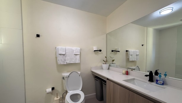 Un baño moderno con inodoro, lavabo, espejo y toallero.