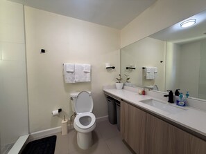 Et moderne badeværelse med toilet, vask, spejl og håndklæderadiator.