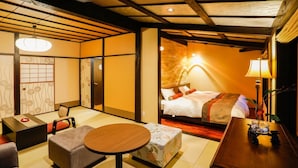 A traditional Japanese-style room with tatami flooring, a low table, a sofa, and a bed with a headboard. - Kinosaki Tenboen (Toyooka)