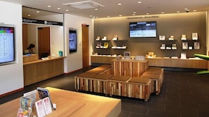 A reception area with a wooden reception desk, seating area, and a television screen on the wall. - Kinosaki Tenboen (Toyooka)