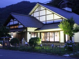 Uma casa japonesa tradicional com telhado inclinado, janelas amplas e um jardim cercado.