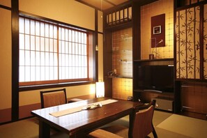 A traditional Japanese room with tatami flooring, a low table, and sliding doors. - Kinosaki Tenboen (Toyooka)