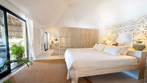 A bedroom with a large bed, a wooden headboard, a bedside table with lamps, and a view of the outdoors. - Lion In The Sun Hotel (Malindi)