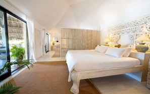 A bedroom with a large bed, a wooden headboard, a bedside table with lamps, and a view of the outdoors. - Lion In The Sun Hotel (Malindi)