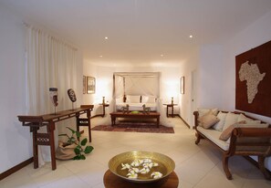 Sala de estar bem iluminada com sofá, mesa de centro, mesa de jantar e cama com dossel.