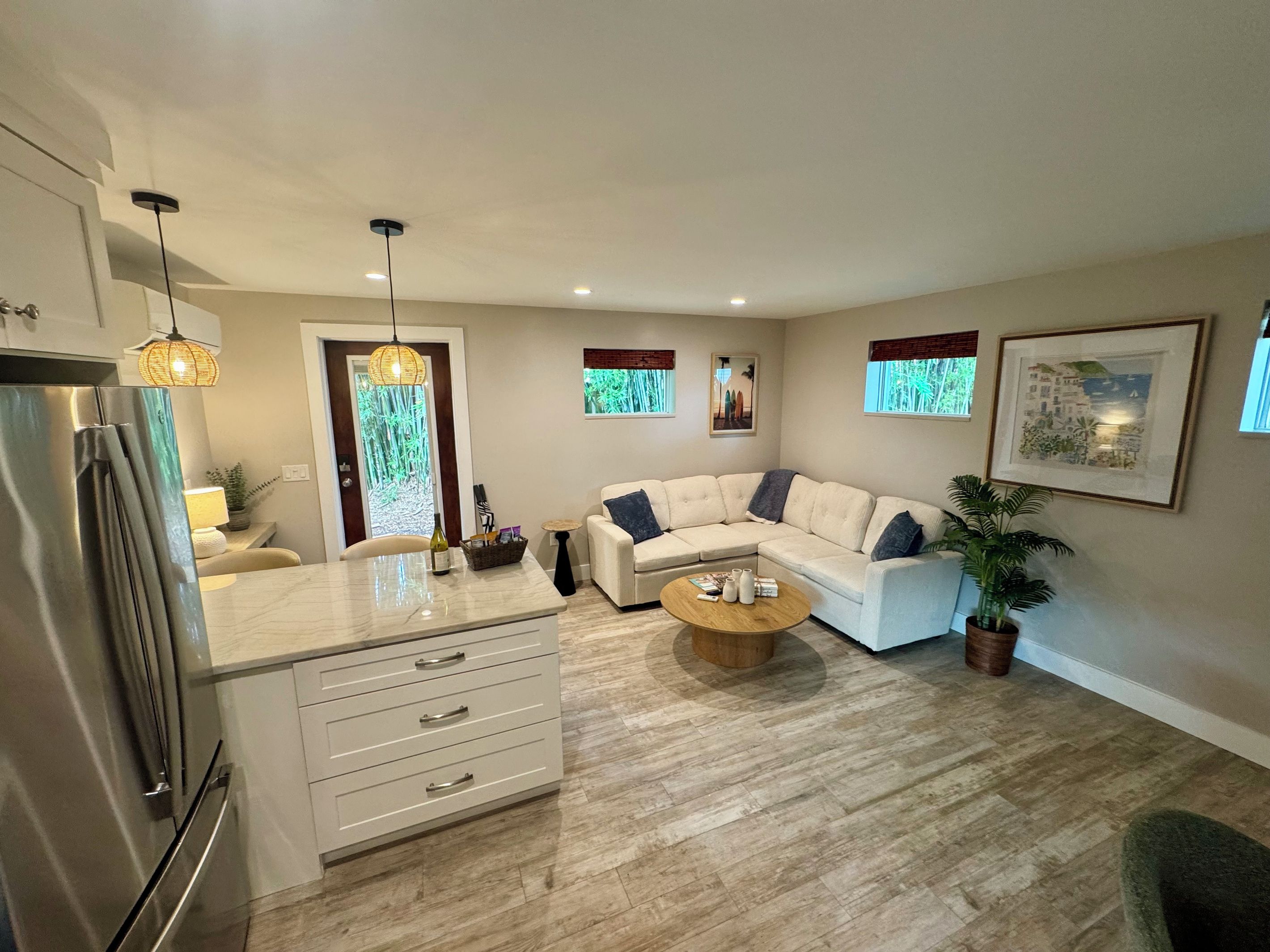 A modern living room with a sectional sofa, a coffee table, and a kitchen area with a refrigerator.