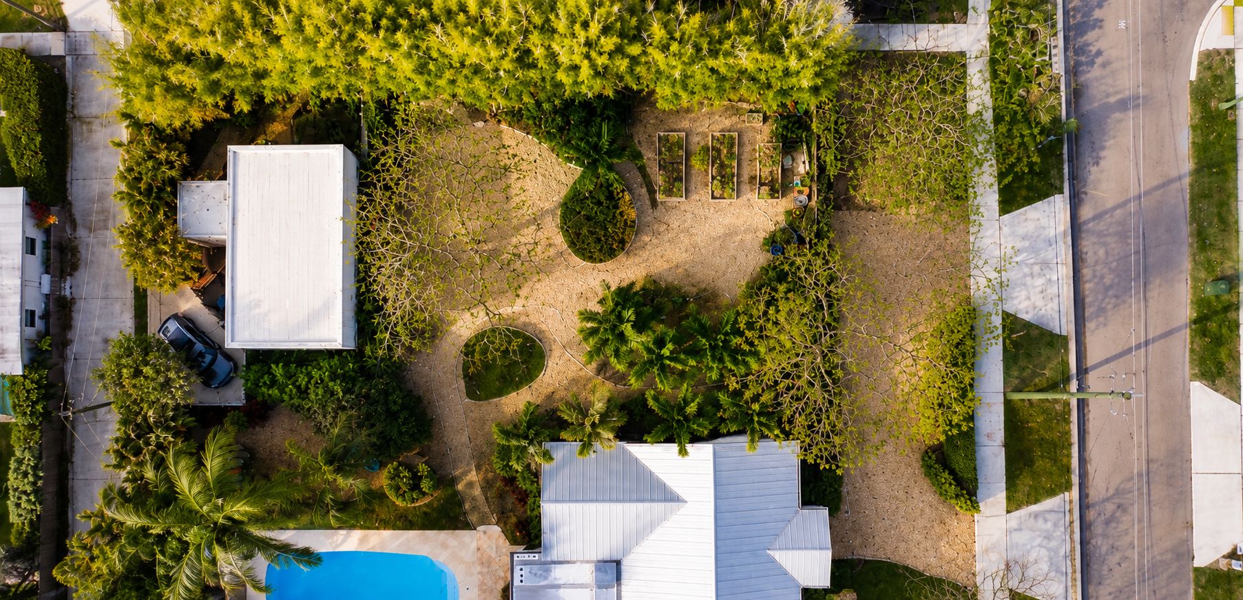 An aerial view of a residential property with a swimming pool, a garage, and a driveway.