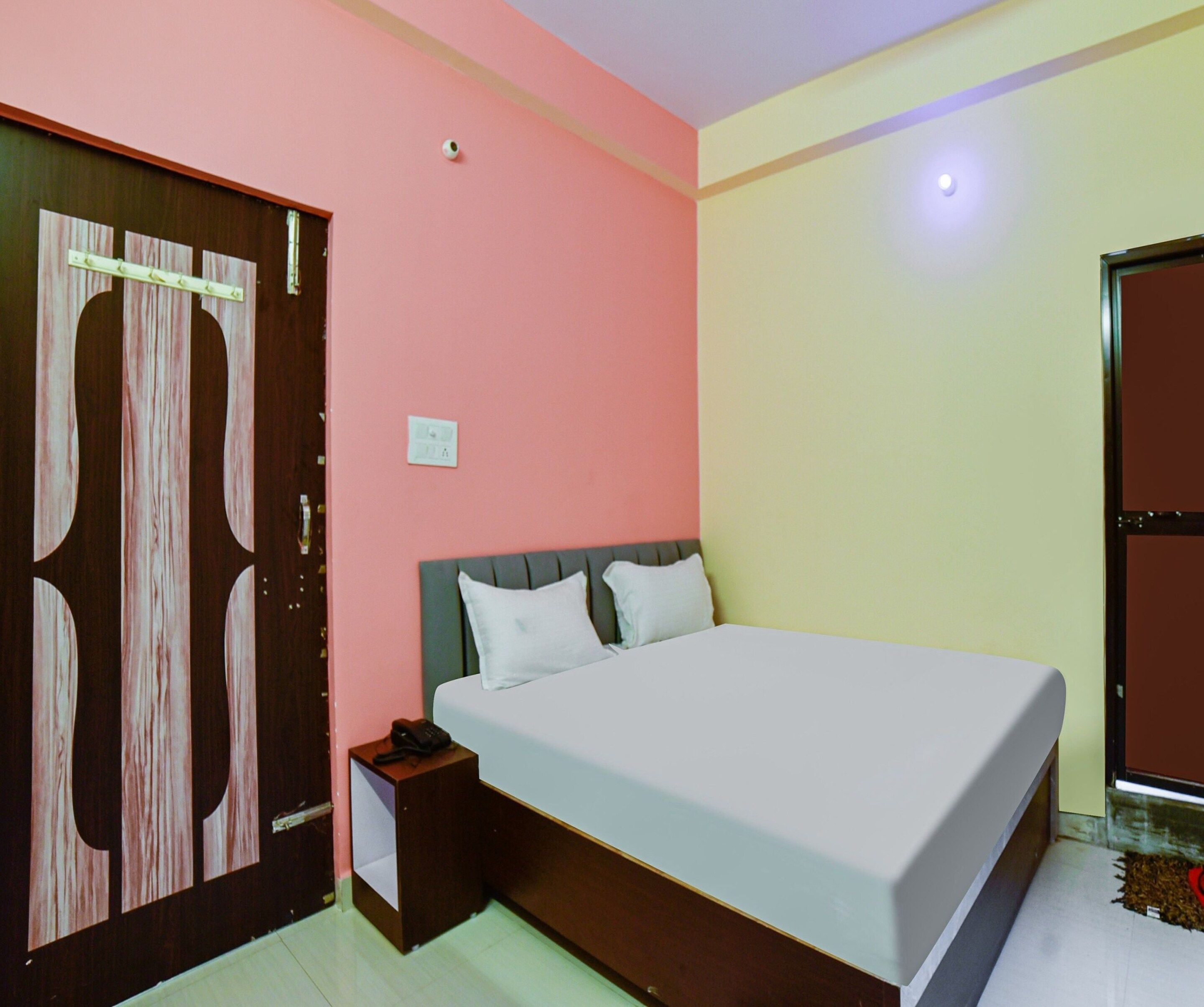 A bedroom with a bed, a nightstand, a wardrobe, and a door.