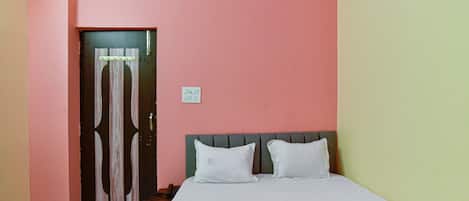 A bedroom with a bed, a nightstand, a door, and a wall switch.