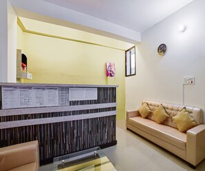 A reception area with a reception desk, a couch, and a clock on the wall.