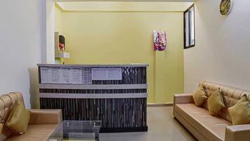 A reception area with a reception desk, two sofas, a glass coffee table, and a wall clock.