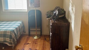 Een kamer met een bed, een staande lamp, een radiator en een deur met een handgreep.