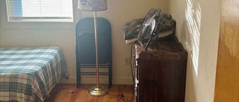 A room with a bed, a standing lamp, a radiator, and a door.