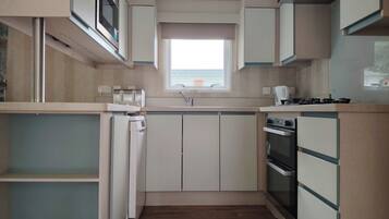 A compact kitchen with a built-in microwave, a sink, and a stove.