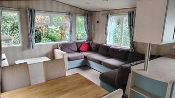A cozy interior with a sectional sofa, a dining table, and a kitchenette area.