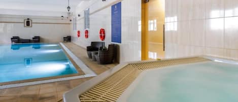 Een zwembadgedeelte met een apart bubbelbad, ligbedden en een receptiebalie.