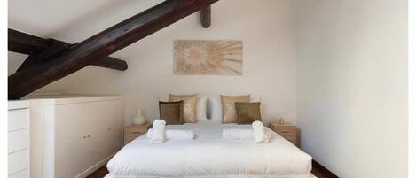 Un dormitorio con una cama grande, una mesita de noche, un aparador y un cuadro en la pared.