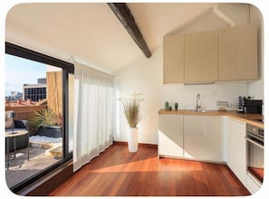 Eine moderne Küche mit weißen Schränken, einer Holz Arbeitsplatte und einem großen Fenster mit Vorhängen.