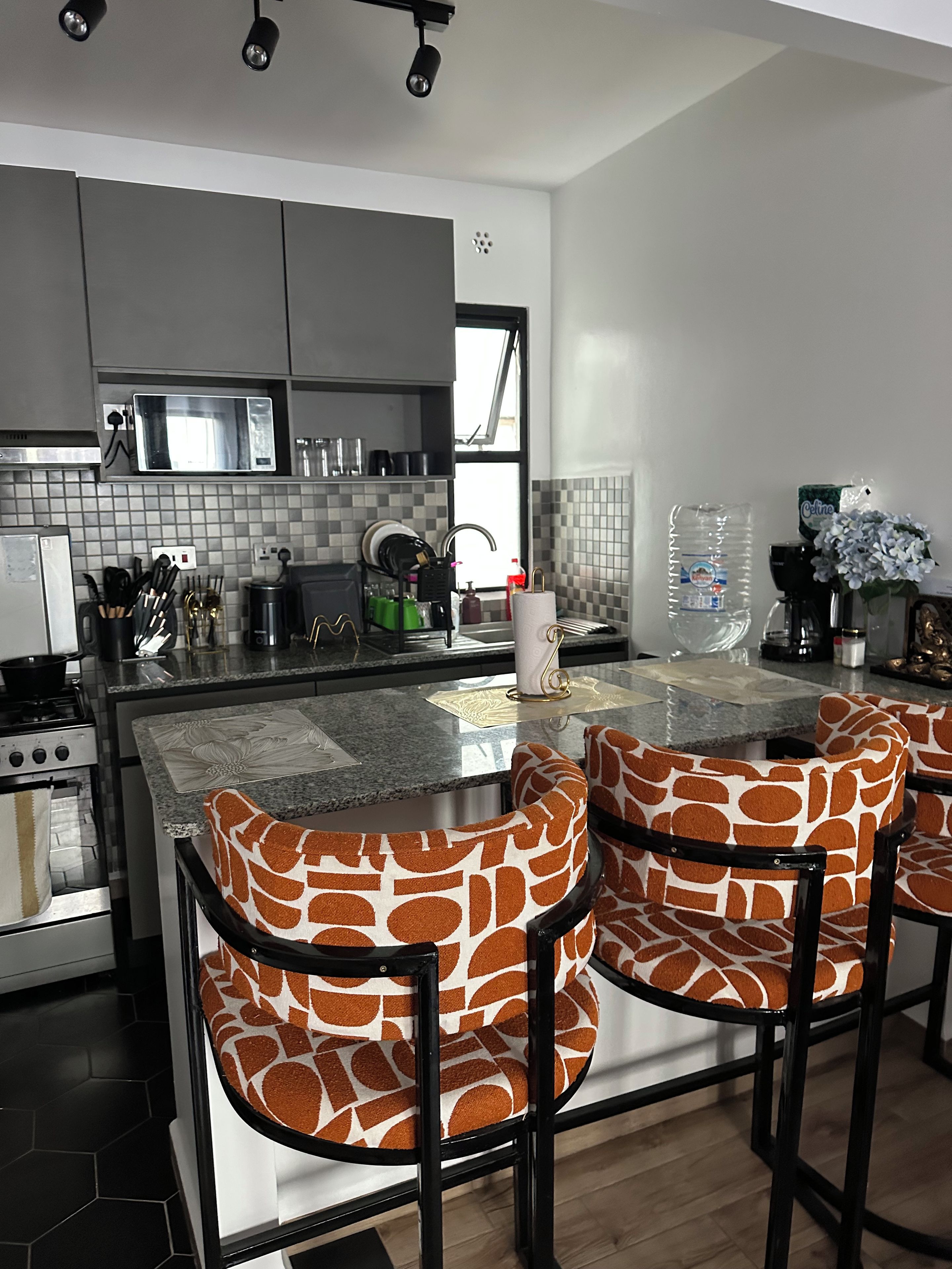 A modern kitchen with a central island, bar stools, and a view of the outdoors.