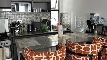 Una cucina moderna con isola centrale, sgabelli da bar e vista sull'esterno.