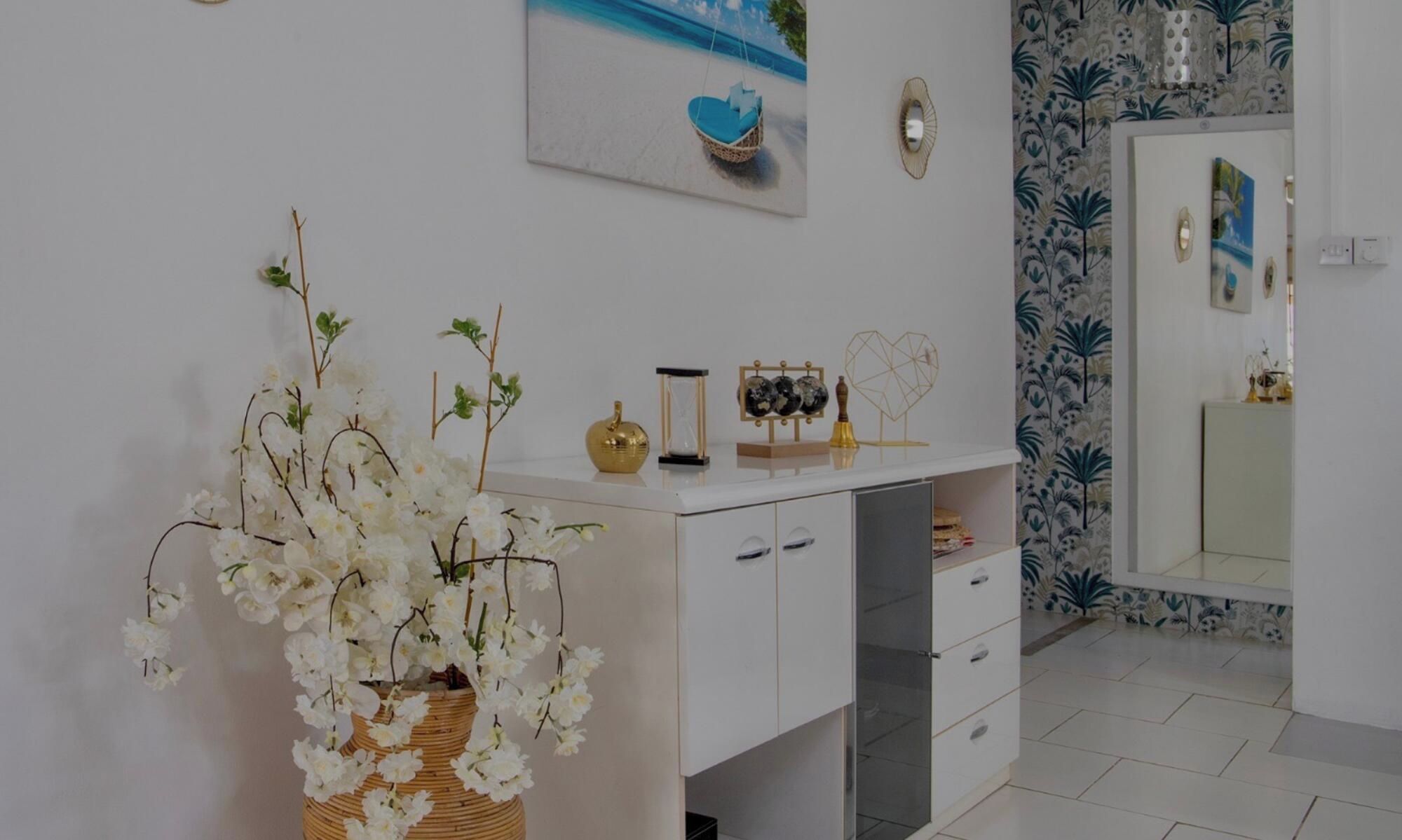 A bathroom with a white vanity, a mirror, and a wall with a tropical wallpaper.