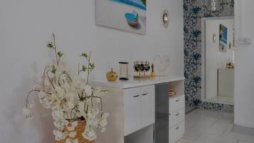 A bathroom with a white vanity, a mirror, and a wall with a tropical wallpaper.