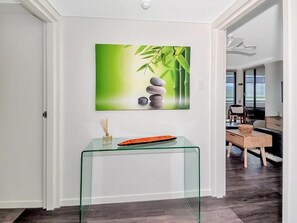 A modern interior with a glass table, a painting of bamboo and stones, and a view to a balcony. - Northshore Tower - Sea Views & City Lights, 2BR on Cairns Esplanade (Cairns)