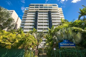 A modern hotel with a prominent entrance, surrounded by lush greenery and palm trees. - Northshore Tower - Sea Views & City Lights, 2BR on Cairns Esplanade (Cairns)