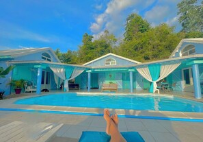 A swimming pool with a view of a house and trees. - Private 50-square-meter cottage with all modern amenities, 24-hour pool access, and a complimentary meal upon arrival (Le Gosier)