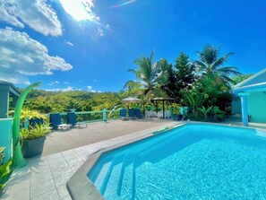 Ein Swimmingpool mit Liegestühlen und Blick auf einen bewaldeten Hügel.