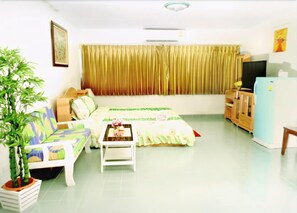 A room with a bed, a sofa, a small table, a television, and a refrigerator. - Donmuang Impact Condo Service (Pak Kret)